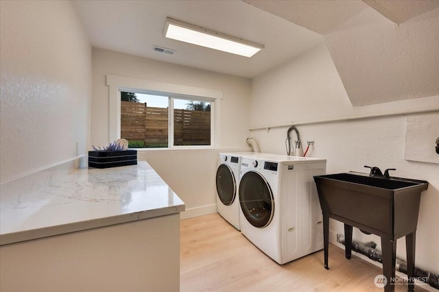 clothes washing area with laundry area, independent washer and dryer, visible vents, and light wood-style floors