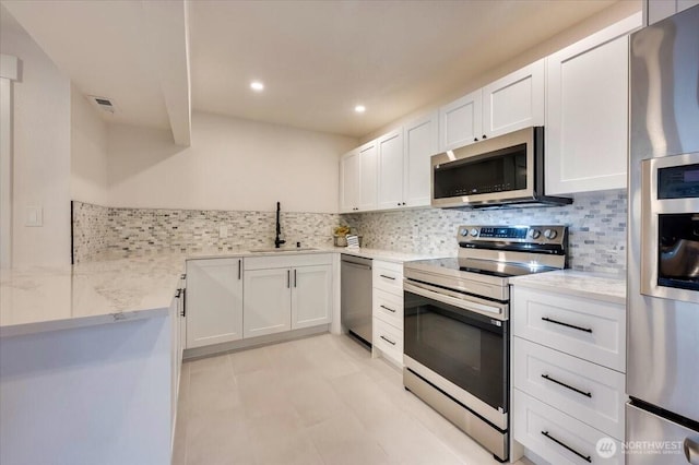 kitchen with light stone counters, visible vents, appliances with stainless steel finishes, white cabinets, and a sink