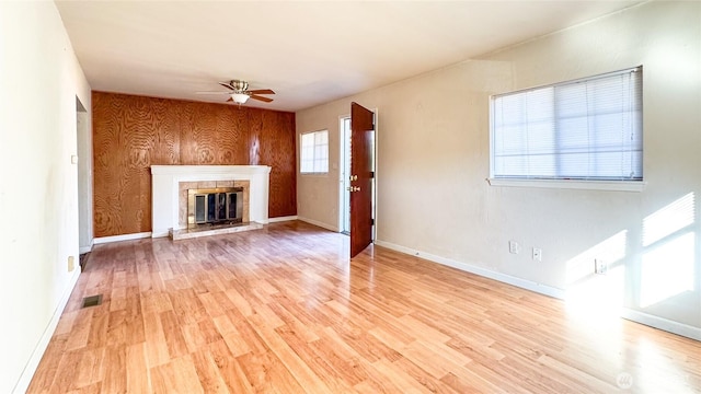 unfurnished living room with light wood-style floors, baseboards, a ceiling fan, and a glass covered fireplace