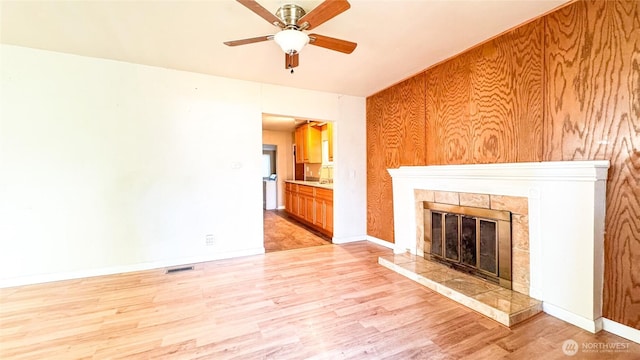 unfurnished living room with light wood-type flooring, visible vents, a fireplace, and baseboards