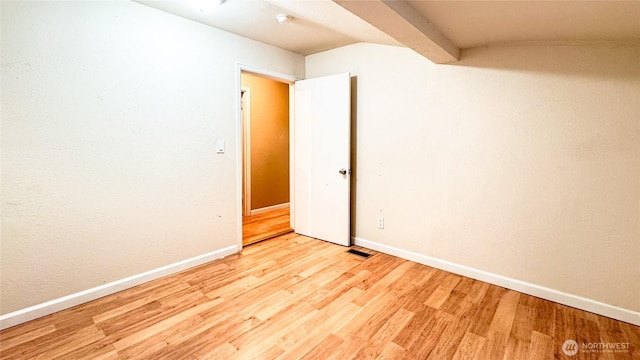 empty room featuring beam ceiling, light wood-type flooring, visible vents, and baseboards