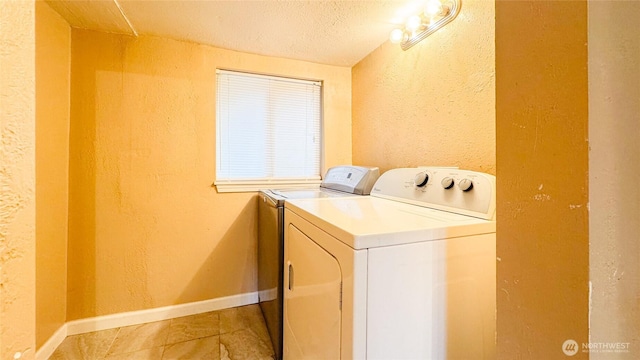 washroom featuring laundry area, baseboards, a textured wall, a textured ceiling, and separate washer and dryer