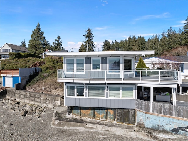 view of front of property featuring board and batten siding, a balcony, and fence