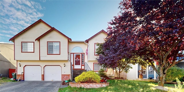 split foyer home with driveway, brick siding, an attached garage, and a front yard