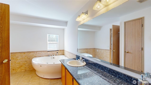 bathroom with tile patterned floors, a tub with jets, tile walls, and wainscoting