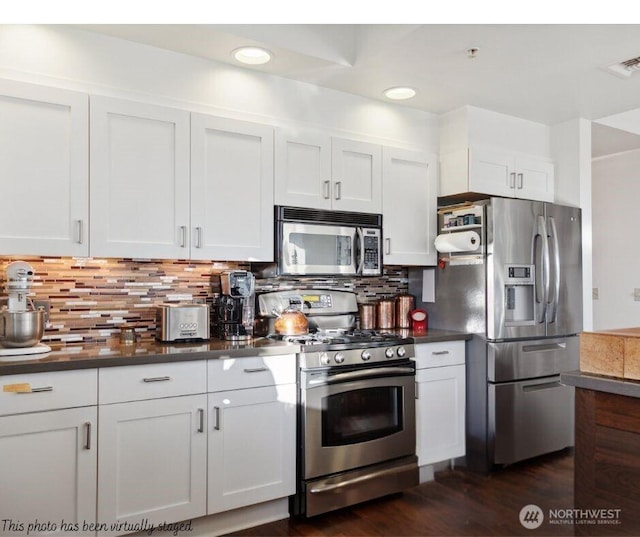 kitchen with visible vents, white cabinetry, appliances with stainless steel finishes, backsplash, and dark countertops