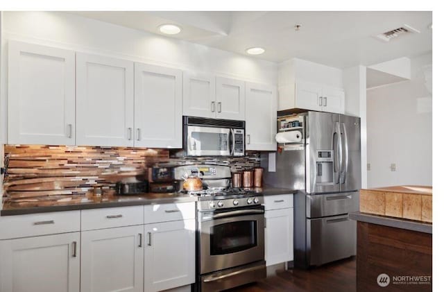 kitchen featuring visible vents, dark countertops, backsplash, appliances with stainless steel finishes, and white cabinets