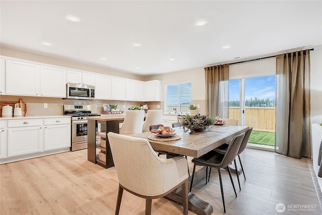 dining space with light wood finished floors and recessed lighting