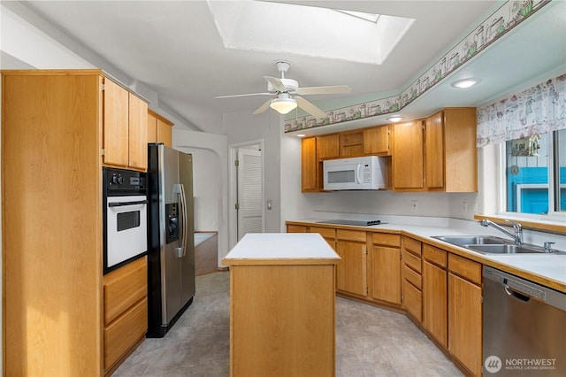 kitchen featuring a sink, a kitchen island, stainless steel appliances, a skylight, and light countertops