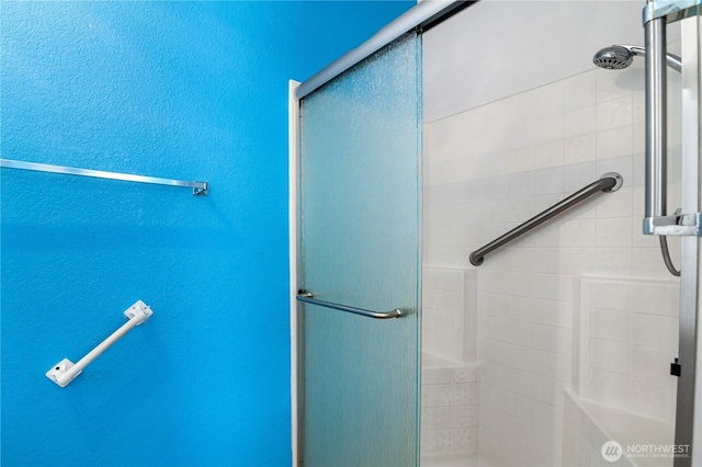 full bath with a shower stall and a textured wall