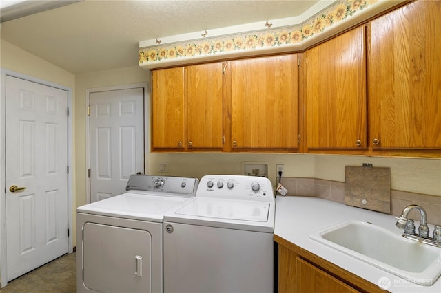 washroom with washing machine and clothes dryer, cabinet space, and a sink