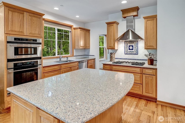 kitchen with light wood-style flooring, a kitchen island, stainless steel appliances, extractor fan, and a sink