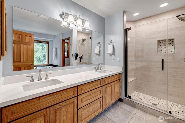 bathroom featuring double vanity, a shower stall, a sink, and tile patterned floors