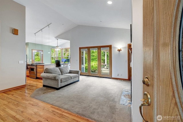 living room with high vaulted ceiling, track lighting, light wood-style flooring, and baseboards