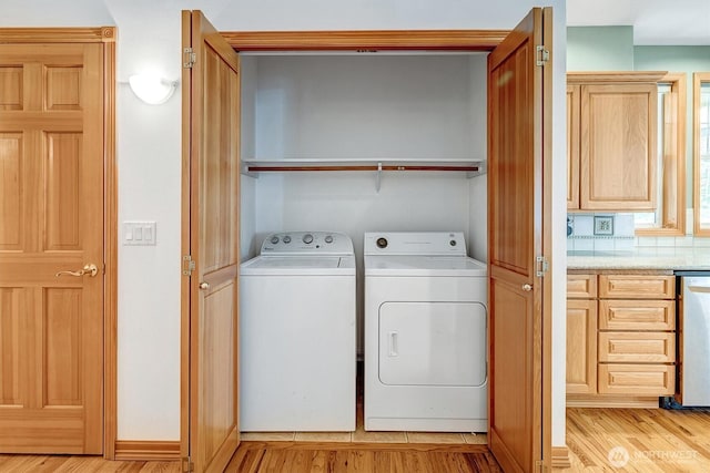 clothes washing area featuring laundry area, light wood-style flooring, and separate washer and dryer