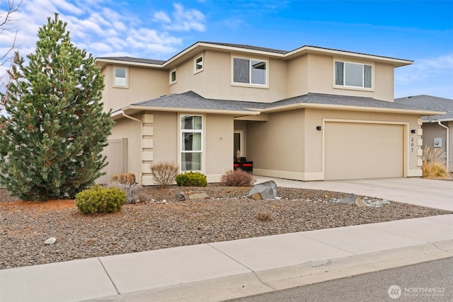 prairie-style home with a garage, roof with shingles, driveway, and stucco siding