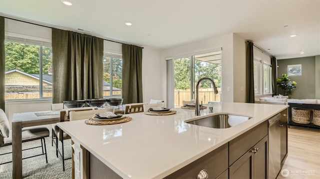 kitchen with light wood-style flooring, a sink, open floor plan, light countertops, and dishwasher