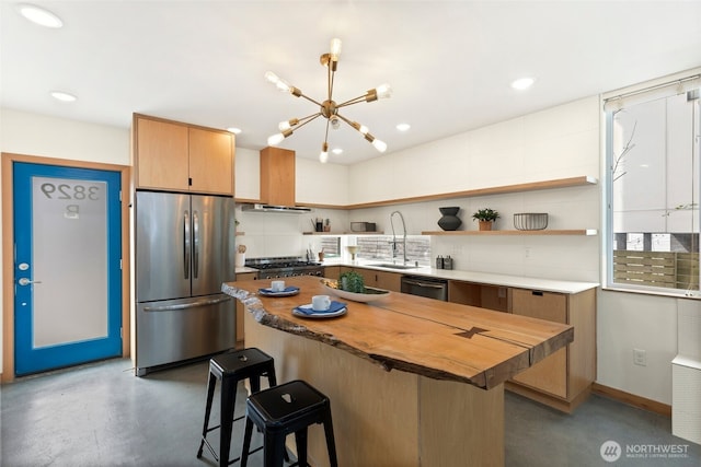 kitchen featuring finished concrete flooring, butcher block countertops, a breakfast bar, appliances with stainless steel finishes, and a sink