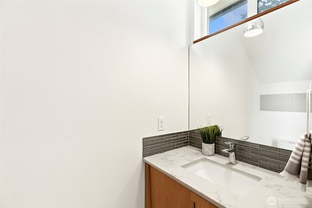 bathroom featuring decorative backsplash, vanity, and vaulted ceiling