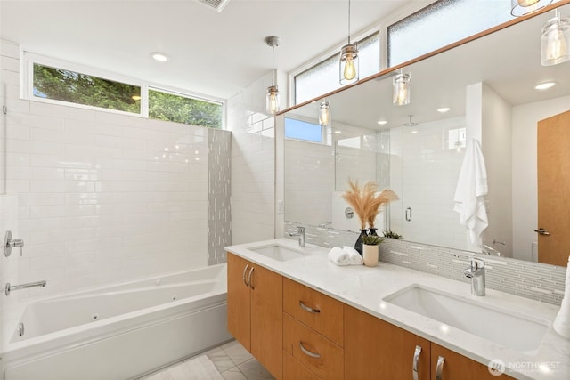 bathroom featuring a sink, backsplash, double vanity, and a combined bath / shower with jetted tub