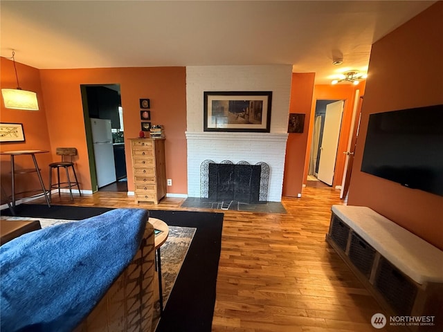 living area with a brick fireplace, baseboards, and wood finished floors