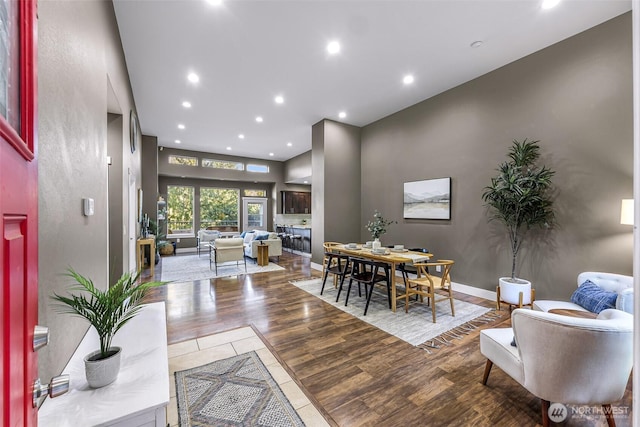 dining area with baseboards, a glass covered fireplace, wood finished floors, and recessed lighting