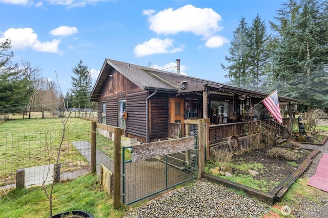 exterior space featuring roof with shingles, fence, a lawn, and log siding