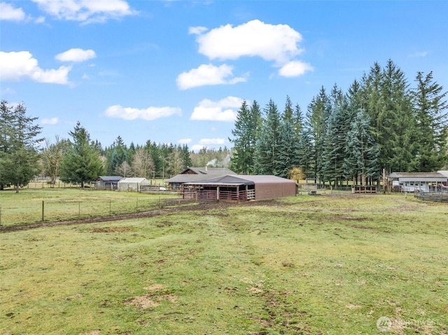 view of yard with a rural view, an outdoor structure, and an exterior structure
