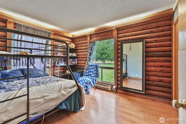 bedroom with a baseboard heating unit, a textured ceiling, log walls, and wood finished floors