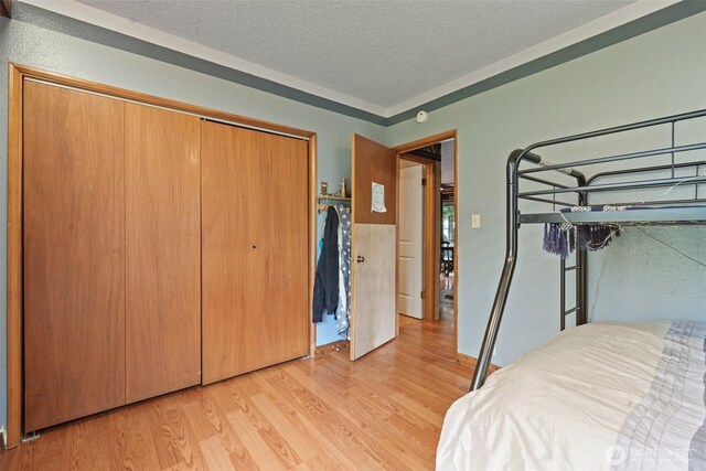 unfurnished bedroom with light wood-style flooring, a closet, and a textured ceiling