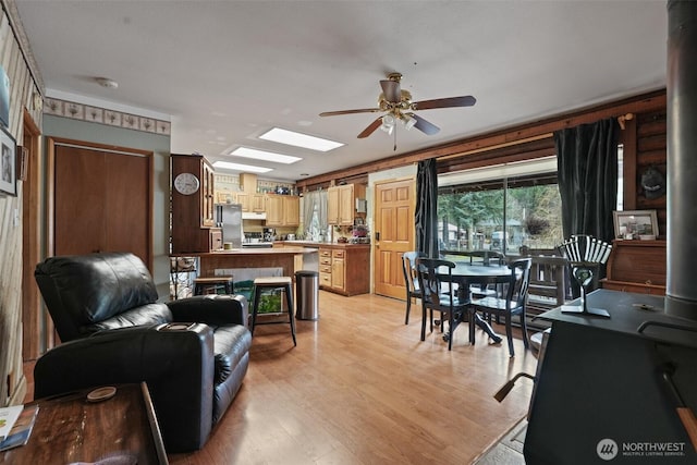 living room with light wood-type flooring, a skylight, and a ceiling fan