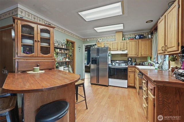 kitchen with under cabinet range hood, wood counters, a kitchen breakfast bar, electric stove, and stainless steel refrigerator with ice dispenser