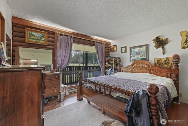bedroom featuring a textured ceiling, rustic walls, wood finished floors, and access to exterior
