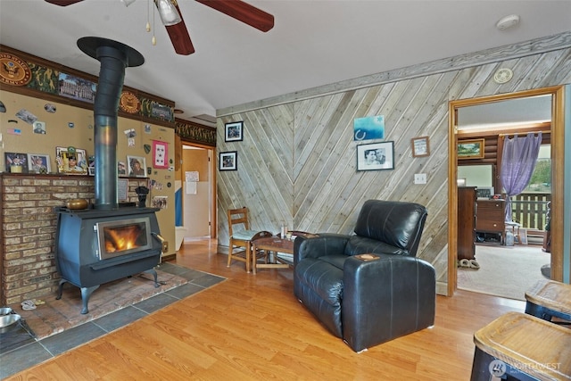 living room with a wood stove, ceiling fan, and wood finished floors