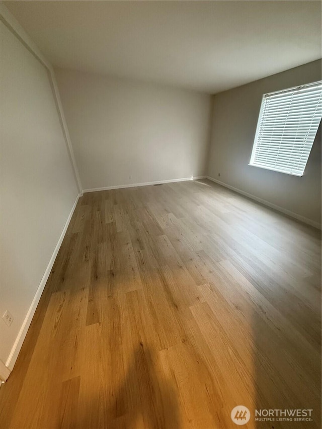 spare room with baseboards and light wood-style flooring