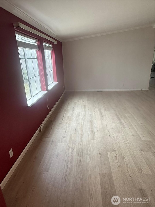 spare room featuring light wood-type flooring, baseboards, and crown molding