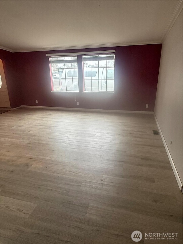 unfurnished room featuring visible vents, wood finished floors, baseboards, and ornamental molding