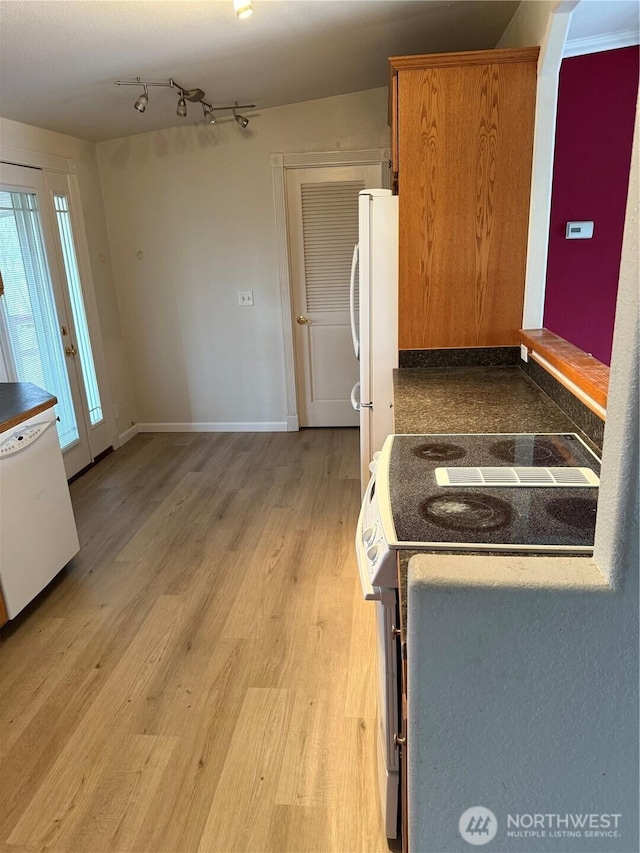 kitchen with light wood finished floors, white appliances, rail lighting, and baseboards