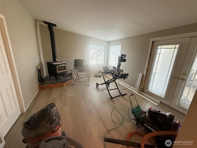 workout area with a wood stove, baseboards, and wood finished floors