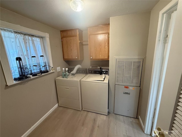 laundry room with baseboards, light wood finished floors, cabinet space, a textured ceiling, and independent washer and dryer