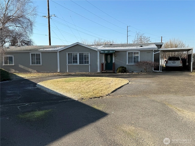 ranch-style home with a carport, driveway, and a front lawn