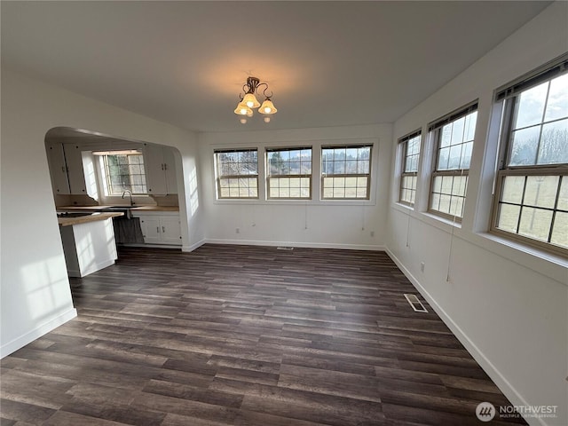 106 Alder St, Pe Ell, WA 98572 - unfurnished dining area with arched walkways, a sink, visible vents, baseboards, and dark wood-style floors