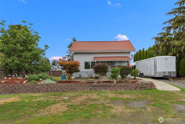 back of house featuring fence and a tiled roof