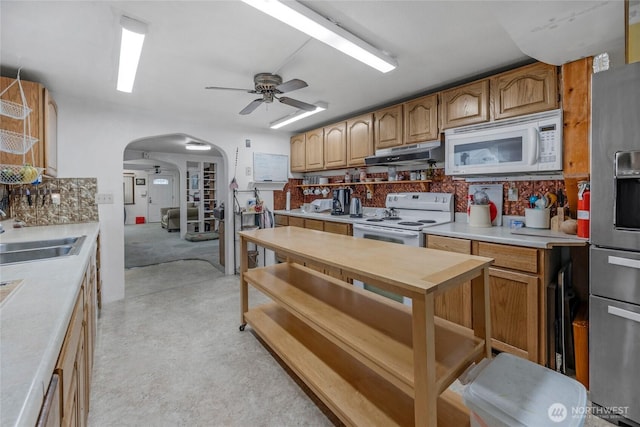 723 E 54th St, Tacoma, WA 98404 - kitchen with arched walkways, under cabinet range hood, white appliances, a sink, and light countertops