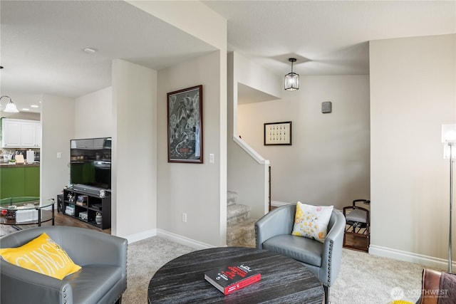 carpeted living area with stairway and baseboards