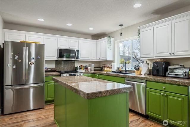 kitchen with green cabinets, stainless steel appliances, a sink, and white cabinetry