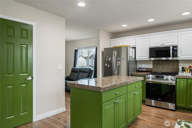 kitchen with appliances with stainless steel finishes, white cabinets, green cabinetry, and wood finished floors