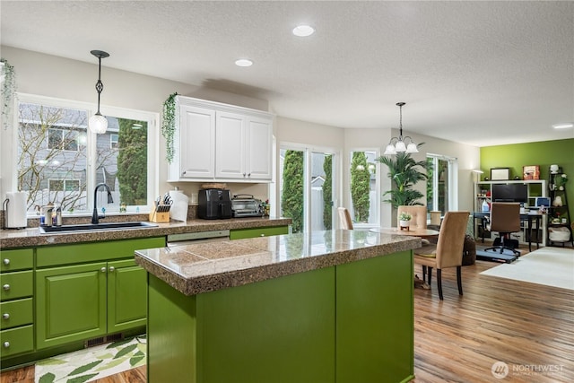 kitchen featuring tile countertops, white cabinets, a kitchen island, a sink, and light wood-type flooring