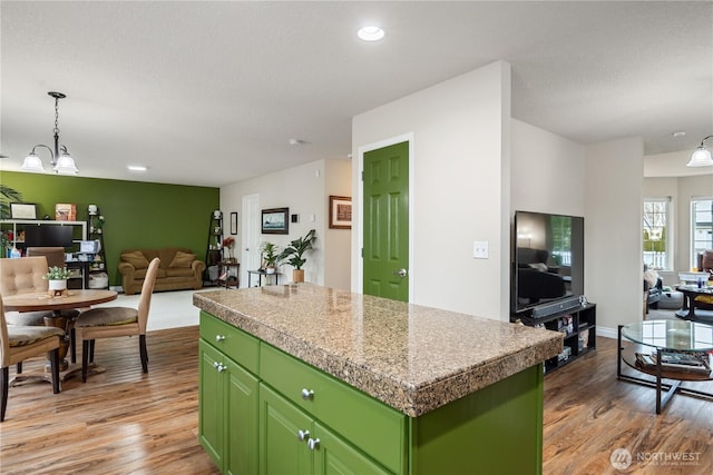 kitchen with an inviting chandelier, light wood-style floors, open floor plan, a kitchen island, and green cabinetry