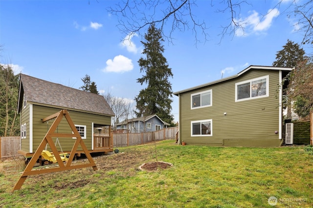 rear view of house featuring a lawn, a wooden deck, fence, and a shingled roof
